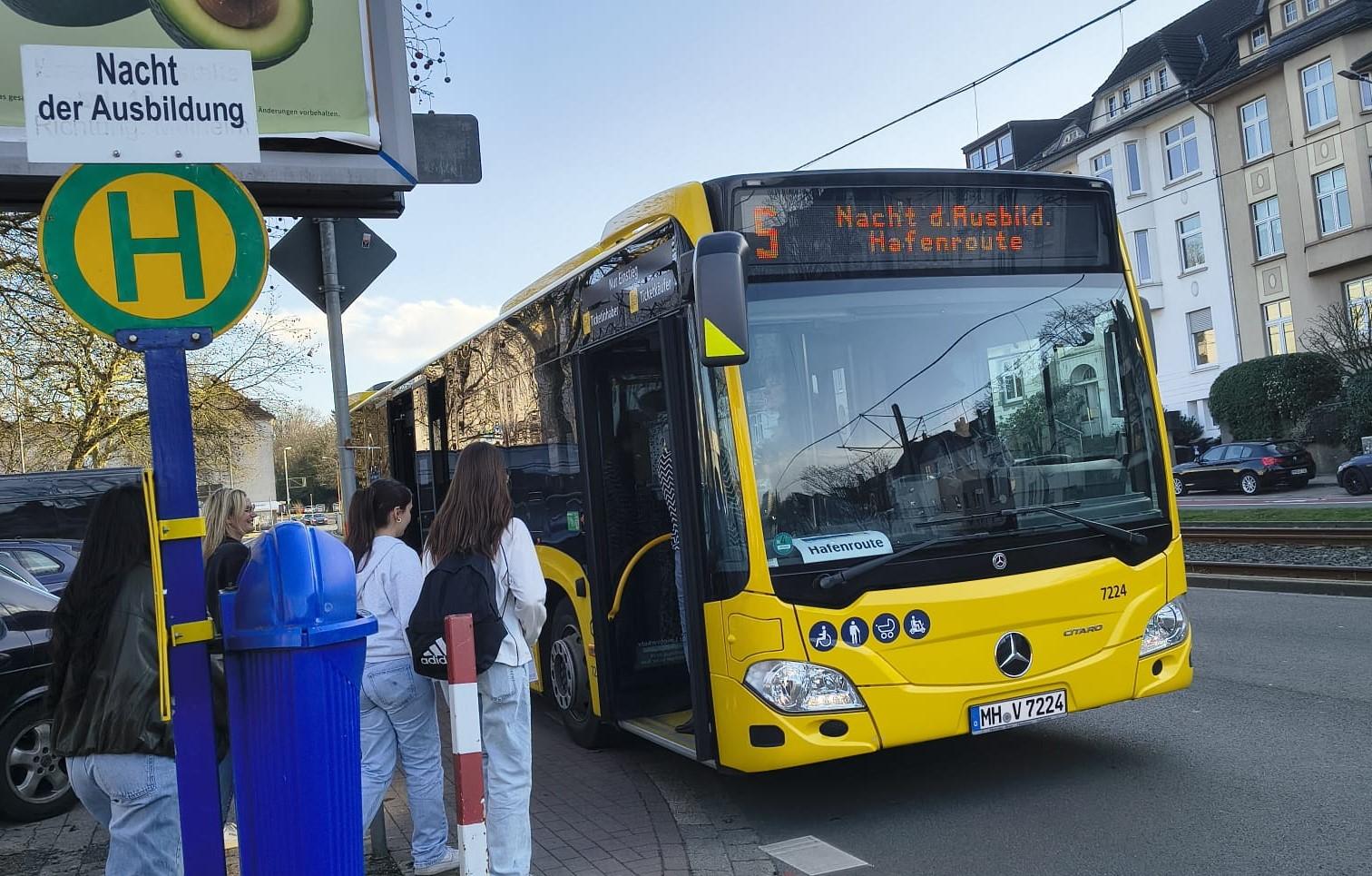Ein gelber Bus stoppt an einer Haltestelle um für eine Sonderfahrt Fahrgäste für die "Nacht der Ausbildung" aufzunehmen.