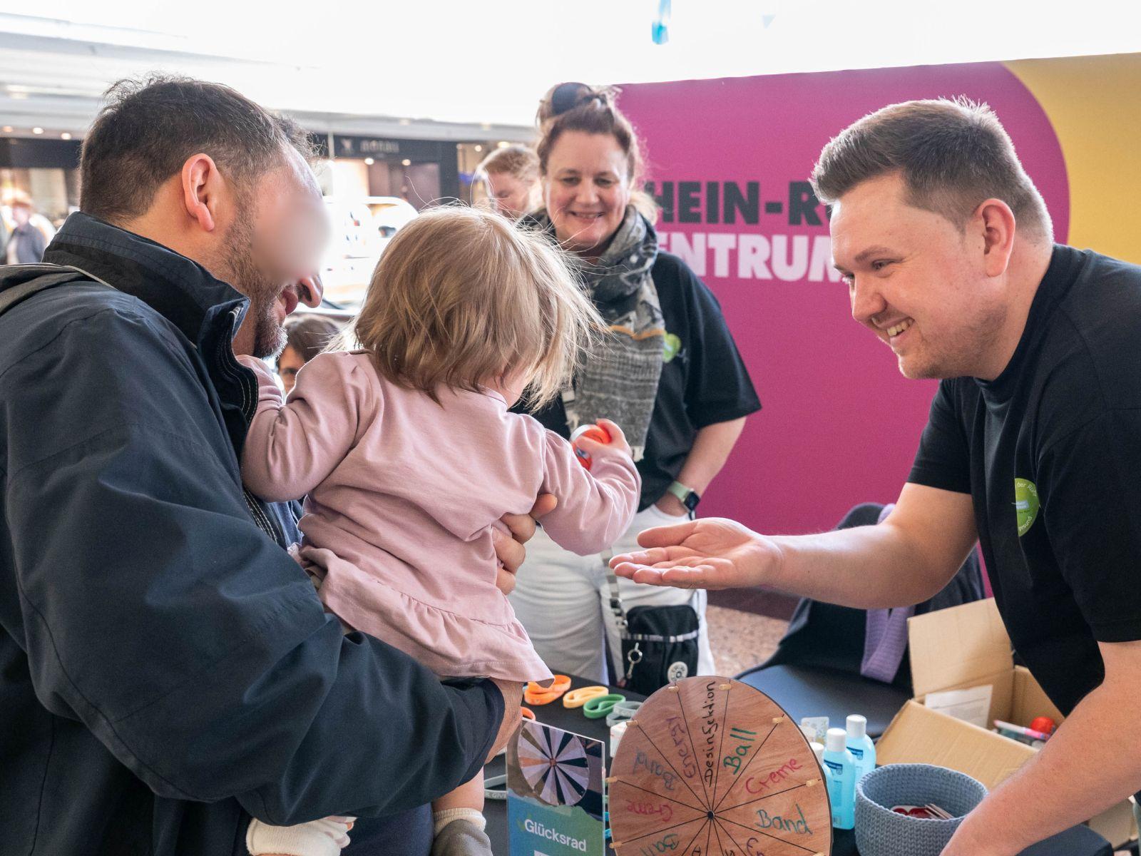 Ein Vater mit seiner Tochter beim Glücksraddrehen