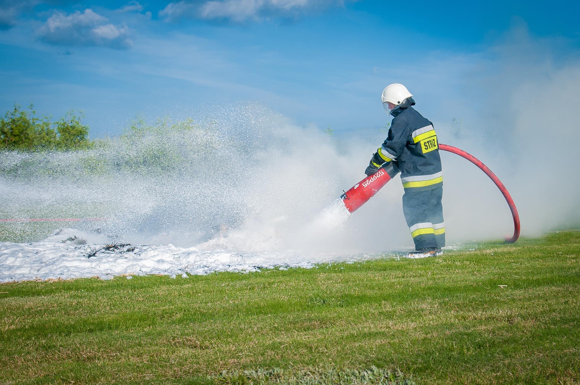 Das Bild zeigt einen Feuerwehrmann, der Löschschaum ausbringt