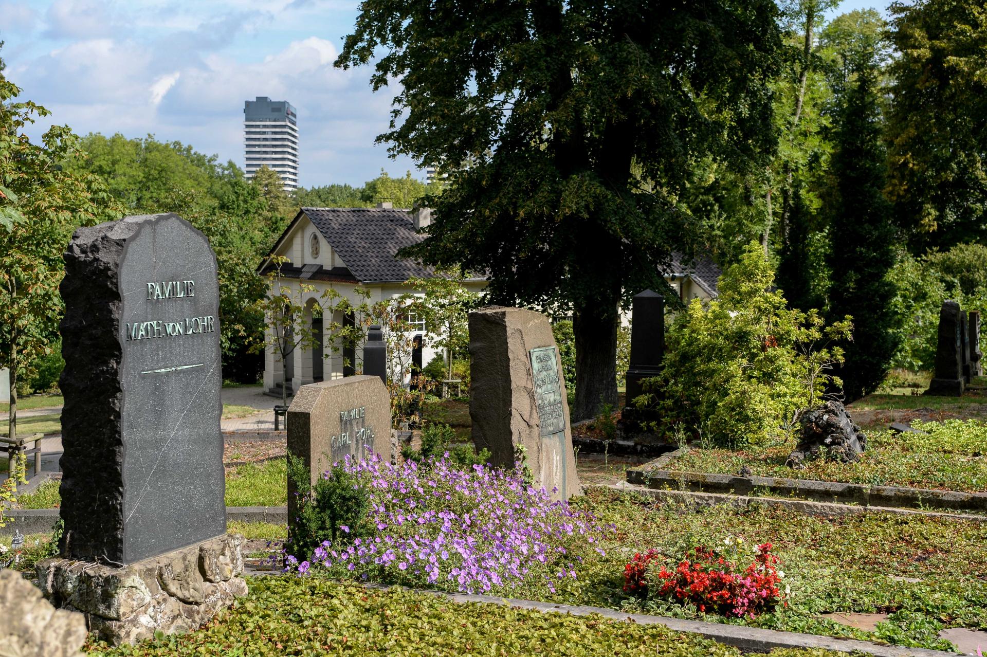 Historische Grabstätten auf dem Altstadtfriedhof vor der Trauerhalle. Im Hintergrund einer der Türme am Hans-Böckler-Platz