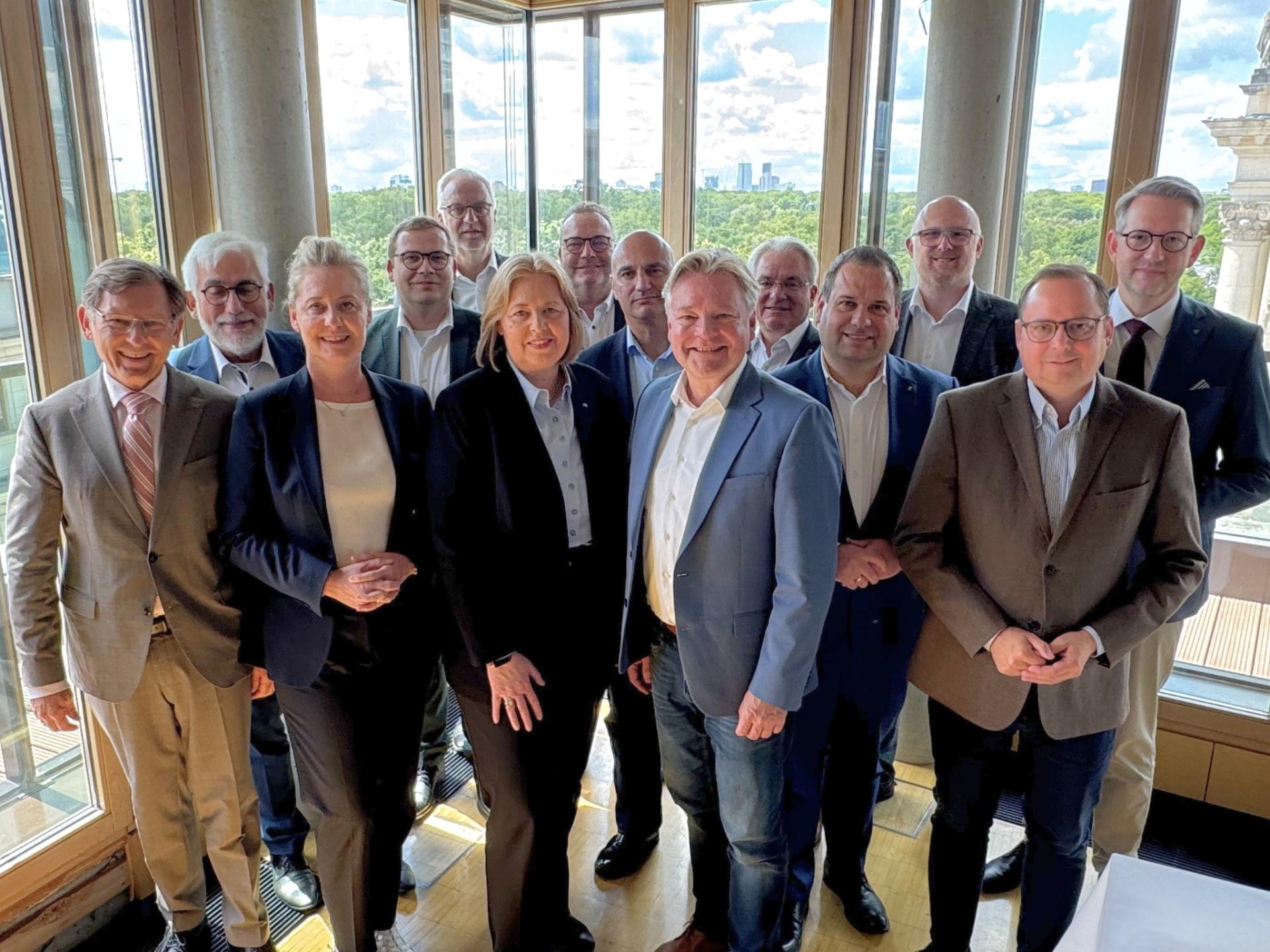 Eine Gruppe Menschen hat sich vor einer Fensterfront für ein Foto aufgestellt.