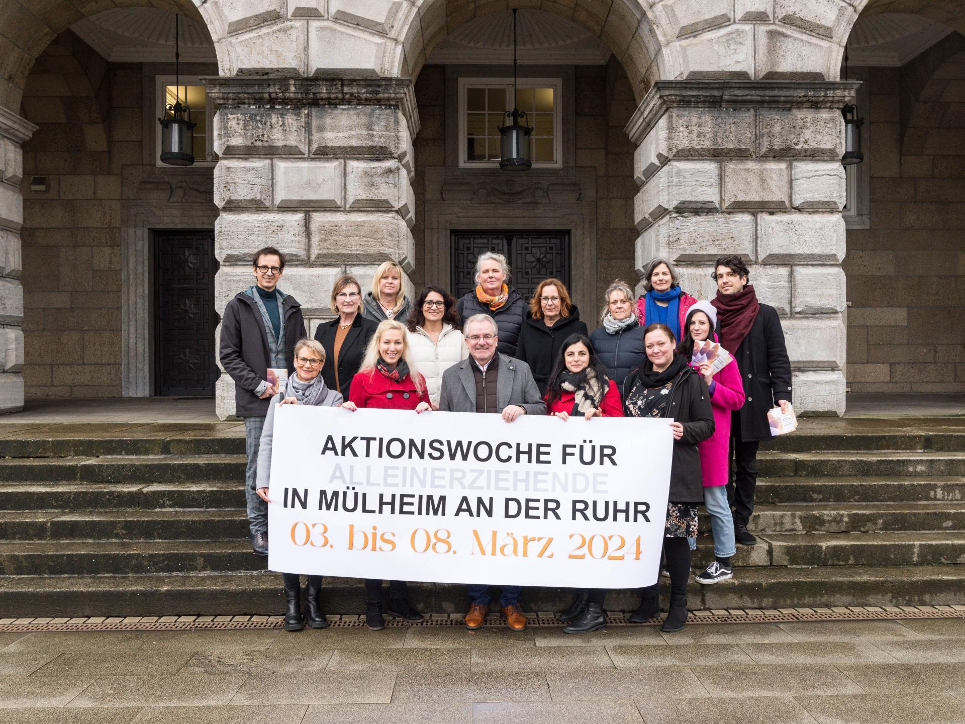 Akteure halten den Banner der Aktionswoche für Alleinerziehende hoch