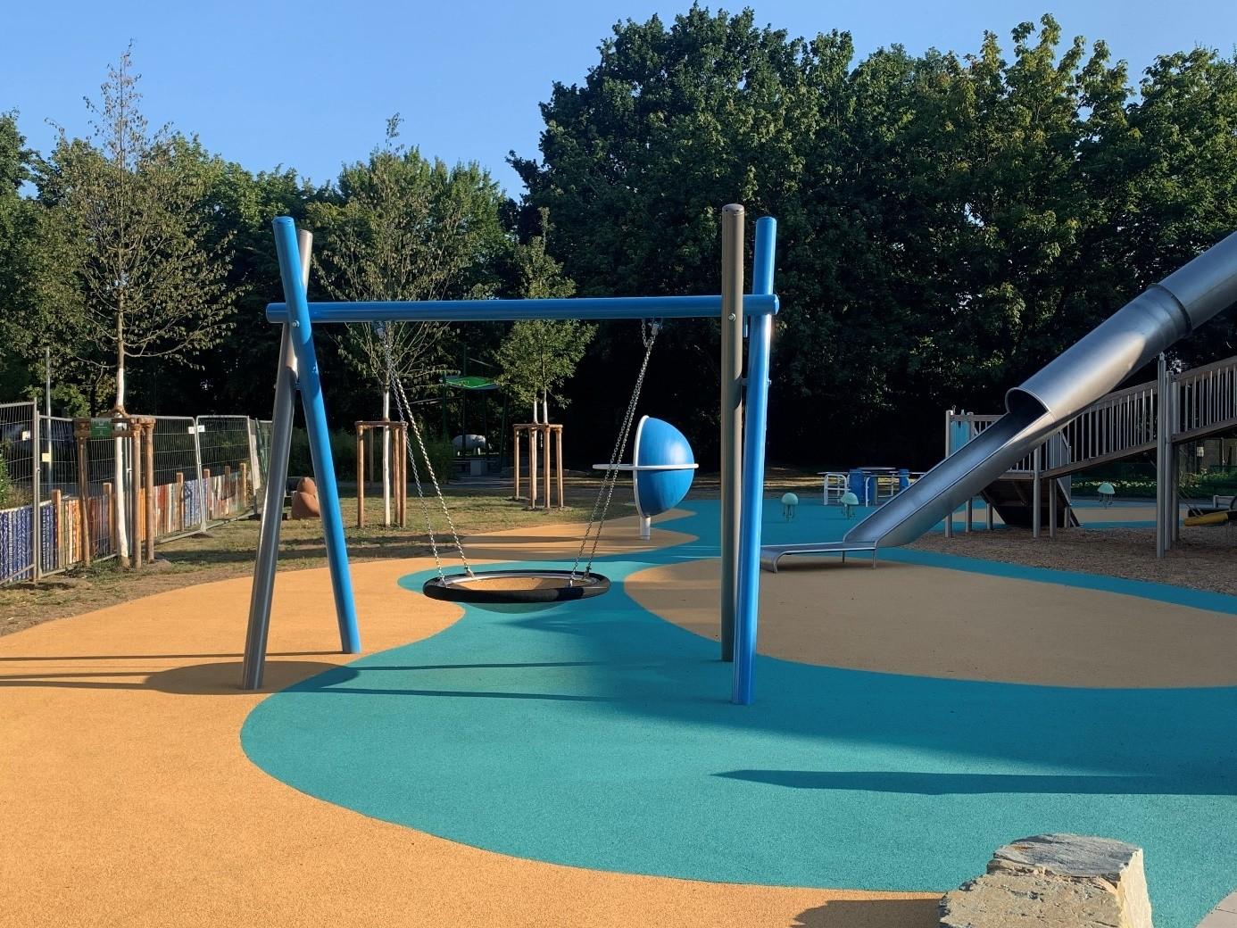 Der inklusive Spielplatz bietet ein Gestell, an dem eine Nestschaukel angebracht ist.