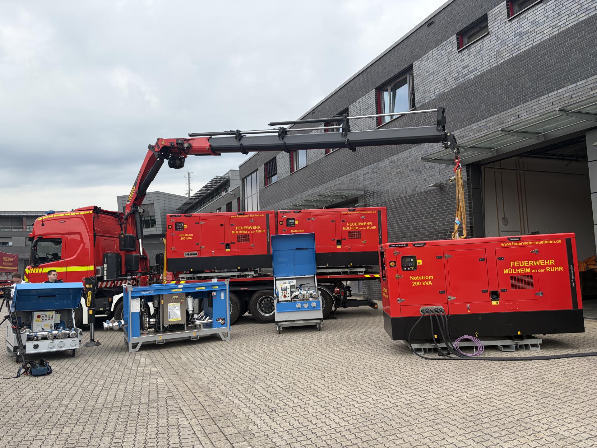 Ein Feuerwehr-LKW mit Kranarm hat ein Notstromaggregat und weitere Materialien für die Notstromversorgung abgeladen.