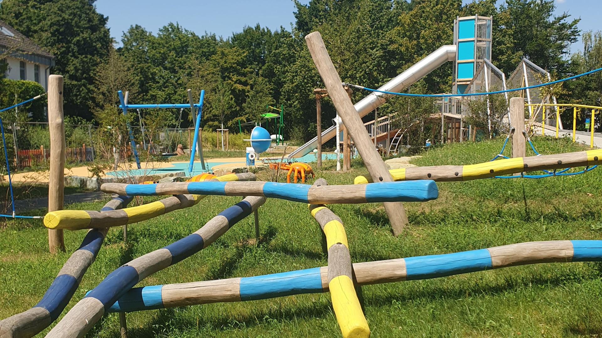 Das Foto zeigt Kletterbalken auf dem Spielplatz am Schloßberg, im Hintergrund ist der Rutschturm zu sehen