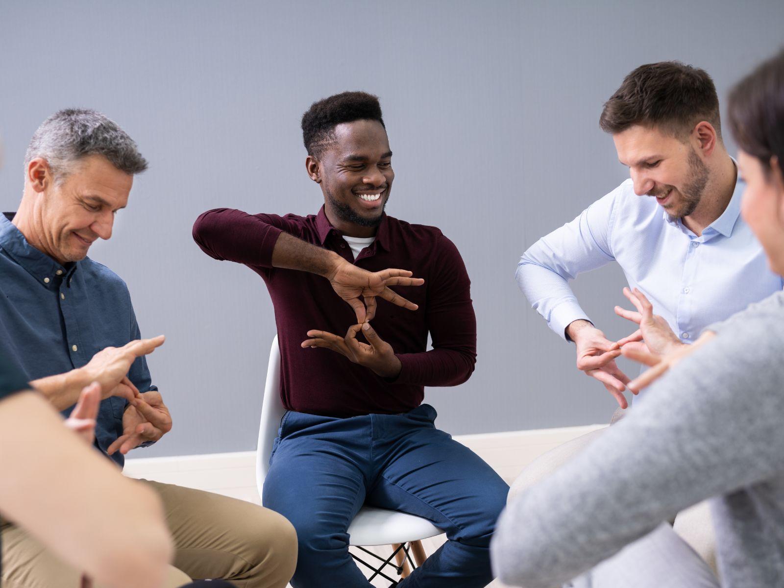 Eine Gruppe von Frauen und Männern erlernt die Gebärdensprache.