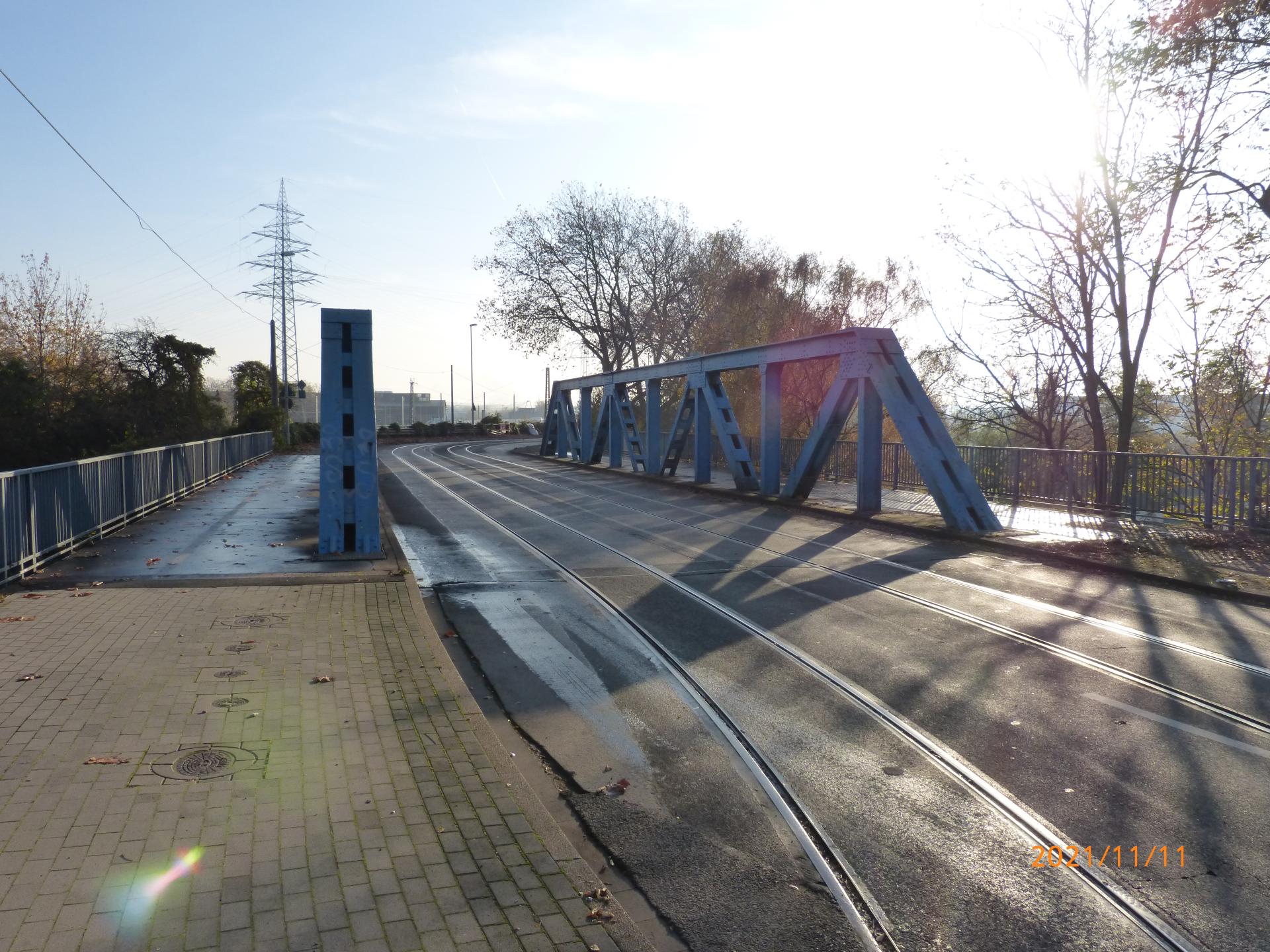 Blaue Stahl-Fachwerkbrücke mit Schienen.